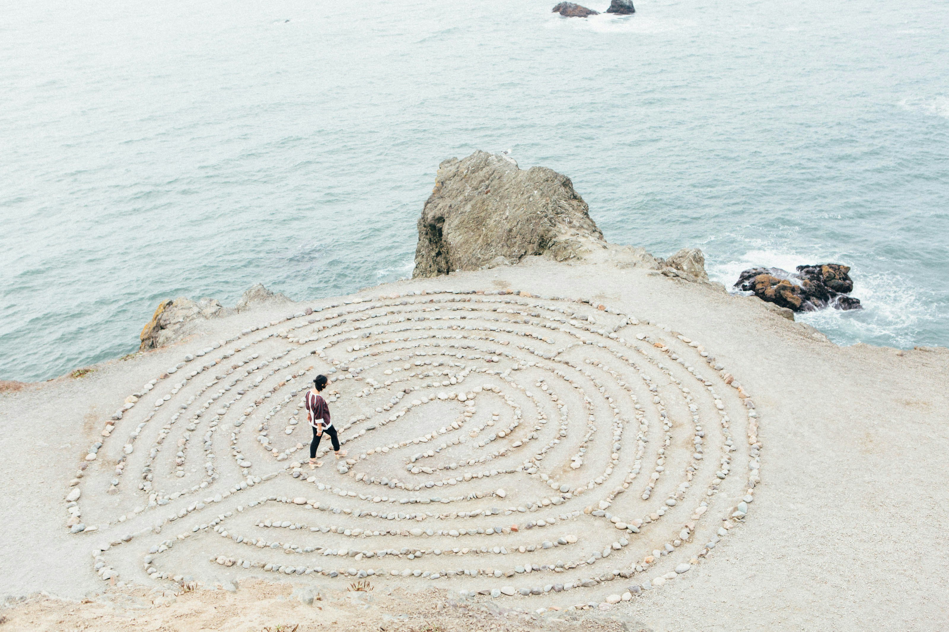 A person walking a spiral labyrinth by the sea