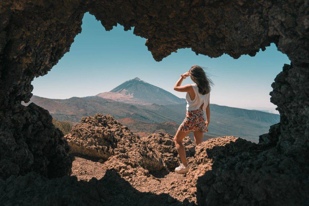 A person looking toward Mount Teide from a rocky viewpoint